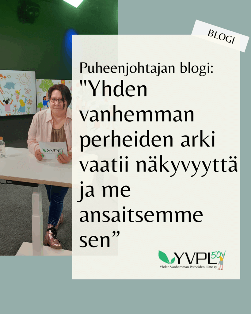 Kuvassa on henkilö, joka seisoo pöydän edessä pidellen paperia. Taustalla on värikkäitä piirustuksia. Kuvassa on myös teksti: Puheenjohtajan blogi: 'Yhden vanhemman perheiden arki vaatii näkyvyyttä ja me ansaitsemme